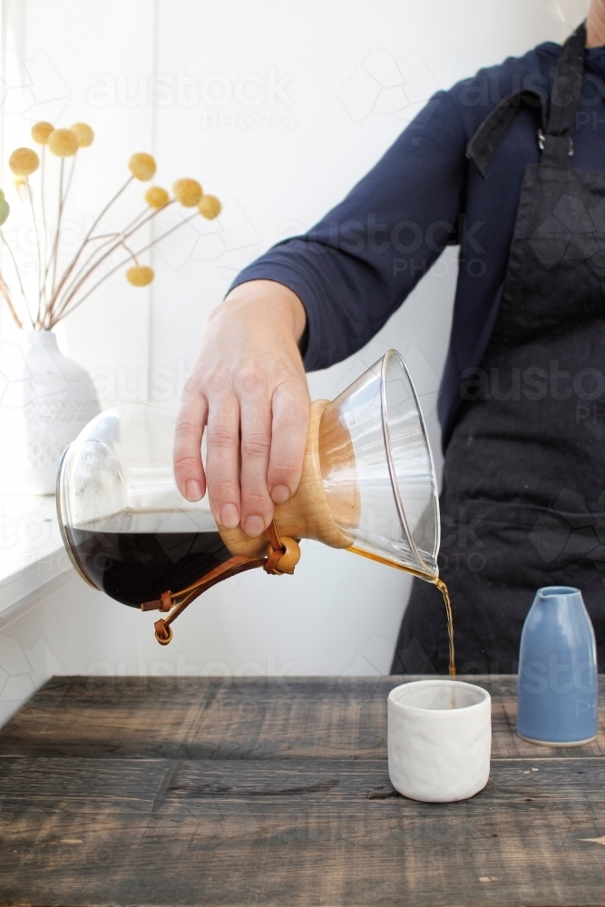 Pouring coffee from chemex into cup - Australian Stock Image