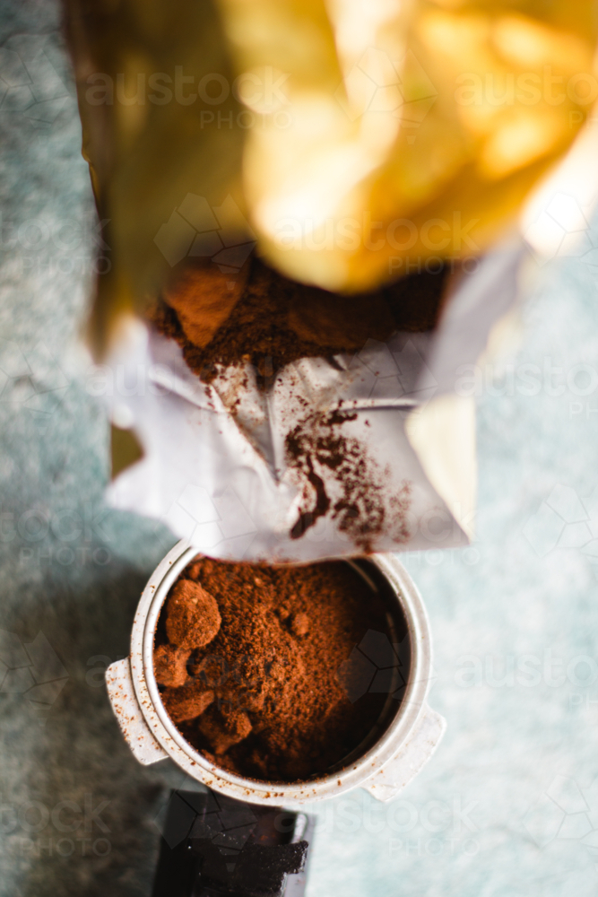 Pouring fresh ground coffee from a bag into an espresso portafilter - Australian Stock Image