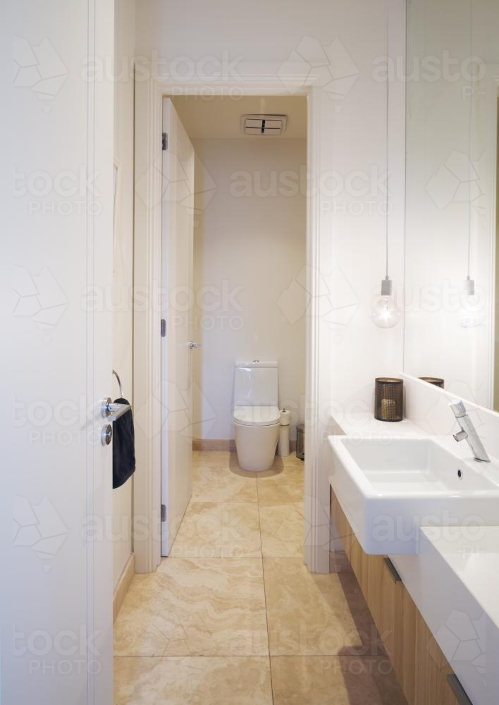 Powder room bathroom with beige tiles and white vanity and pendant lighting - Australian Stock Image