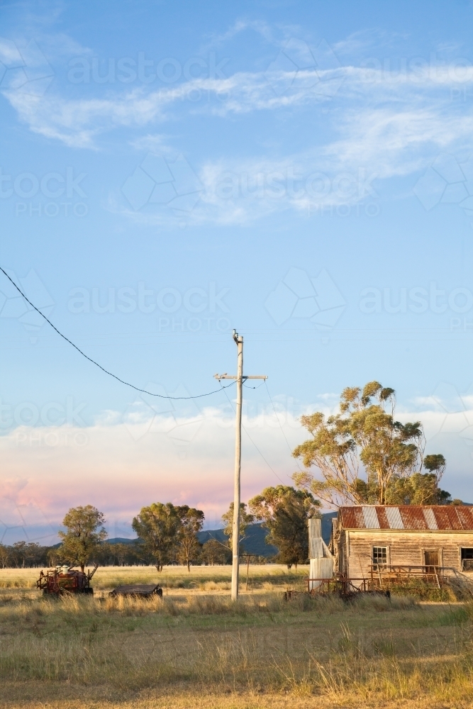 Power pole and line with old farm shed building on property - Australian Stock Image