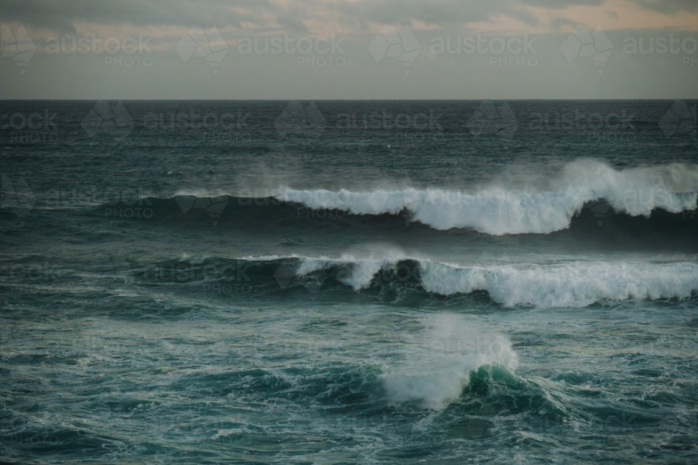 Powerful ocean waves crashing beneath grey cloudy sky - Australian Stock Image
