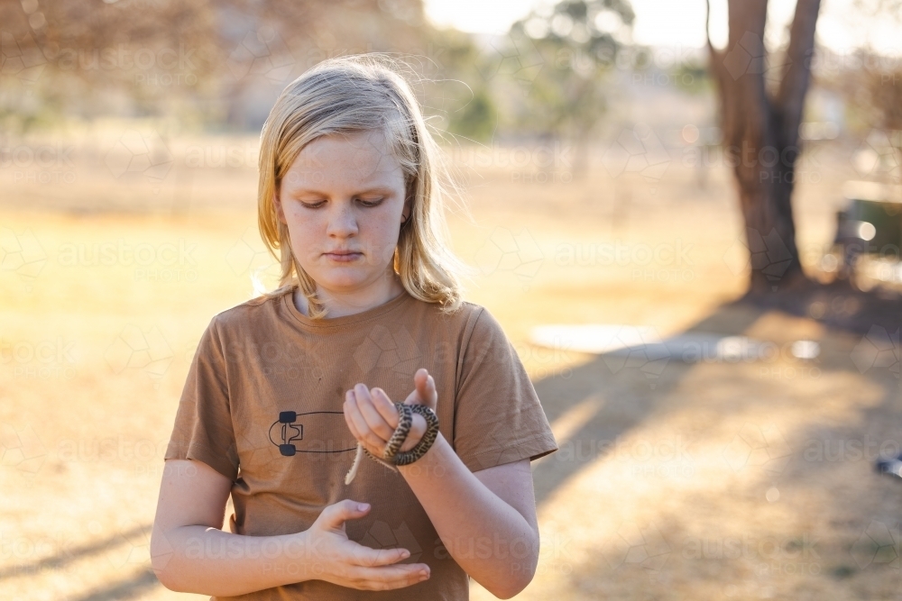 Pre-teen adolescent boy holding pet children's python snake - Australian Stock Image