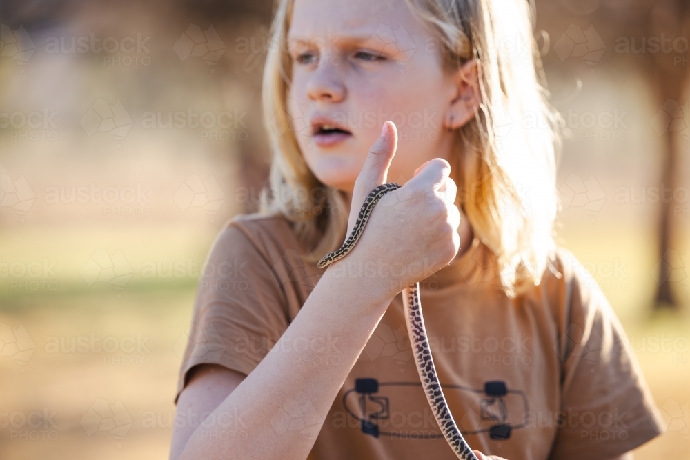 Pre-teen adolescent boy holding pet children's python snake - Australian Stock Image