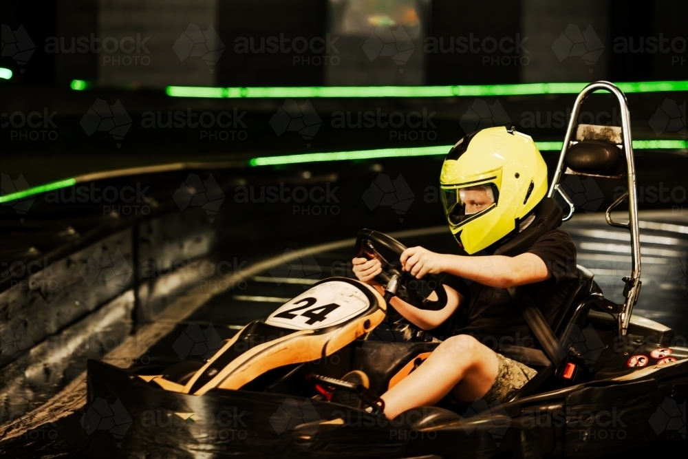 Pre-teen boy driving Go Kart on indoor race track circuit - Australian Stock Image