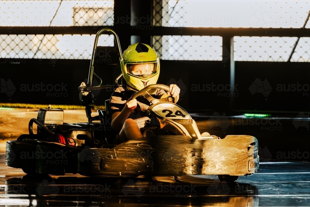 Pre-teen boy driving Go Kart on indoor race track circuit - Australian Stock Image