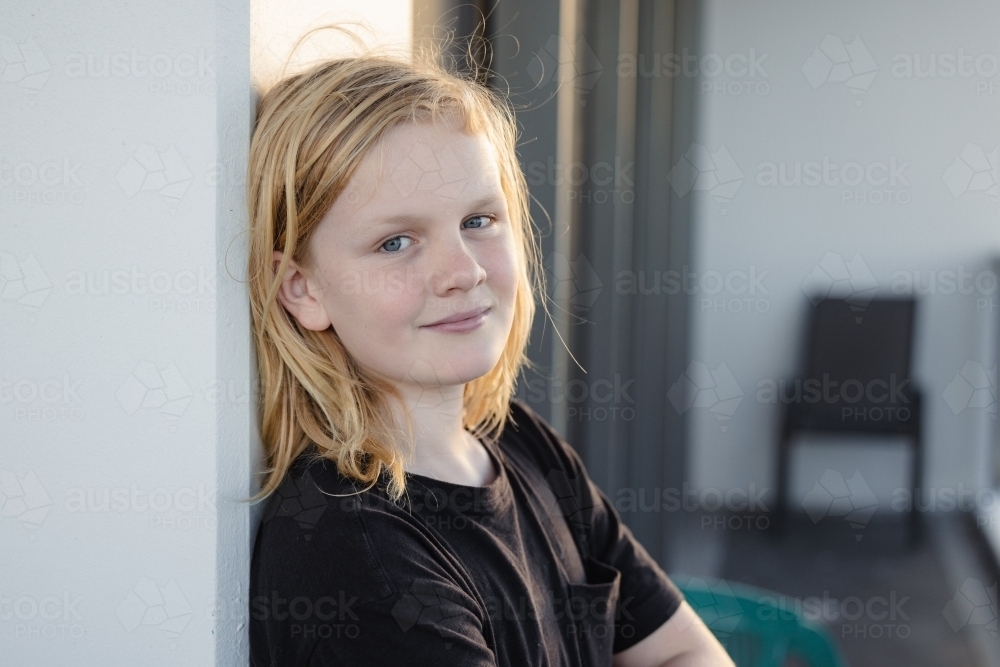 Pre-teen boy leaning against wall on balcony of high rise building on the Gold Coast - Australian Stock Image