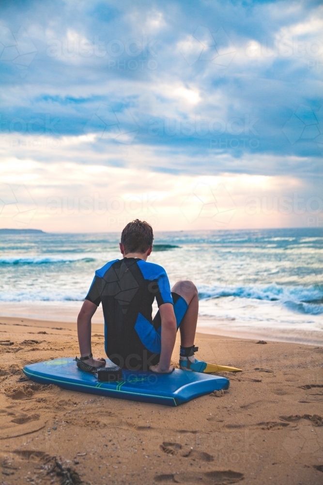 Pre-teen boy preparing to go body boarding at beach - Australian Stock Image