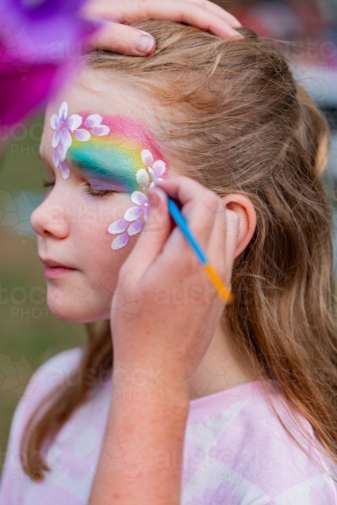 Pre-teen girl having face paint done at event - Australian Stock Image