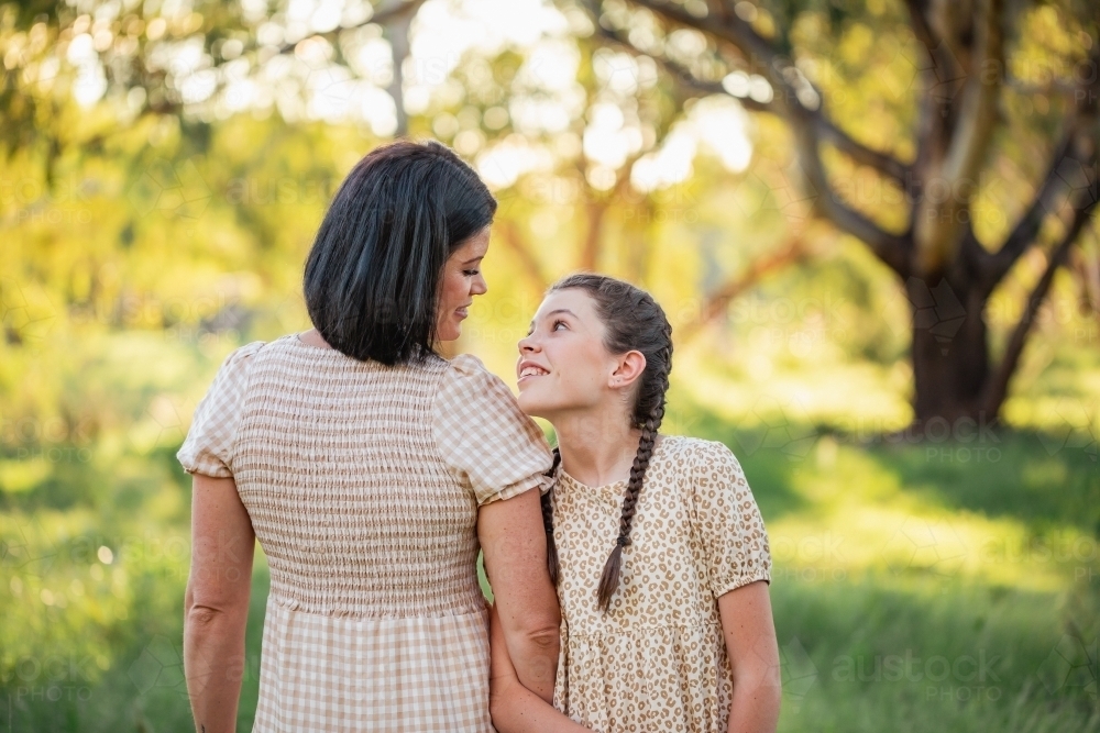 Pre-teen girl leaning on mother&#39;s shoulder in natural bush setting - Australian Stock Image