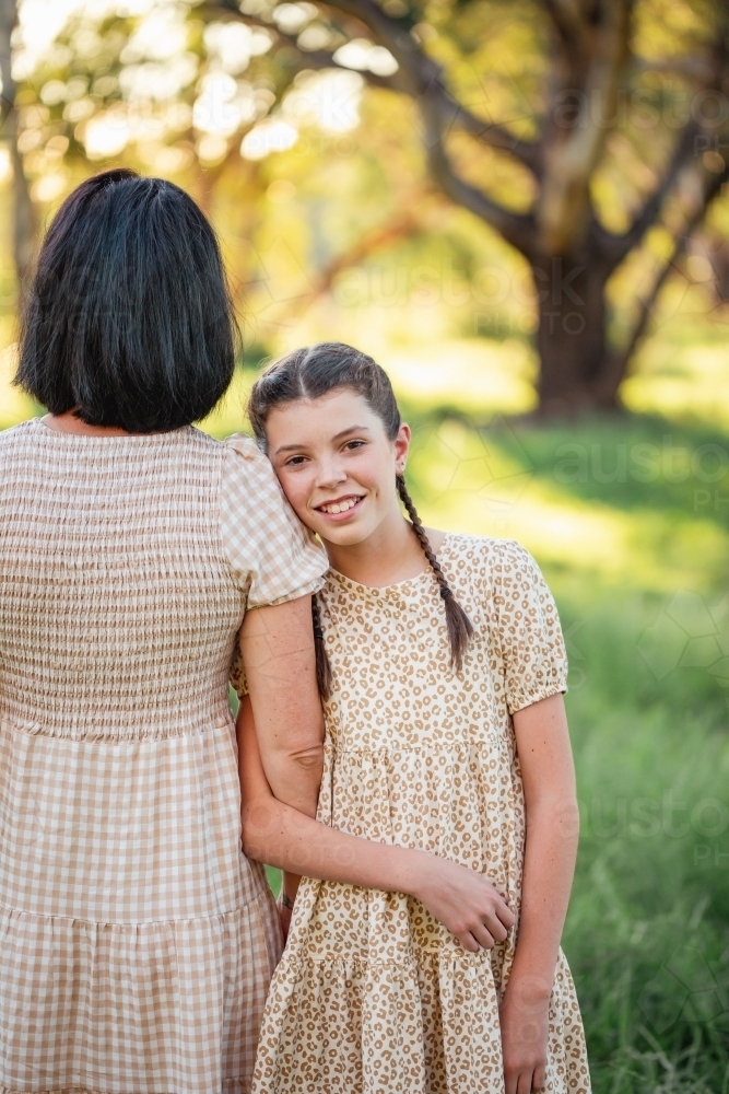 Pre-teen girl leaning on mothers shoulder in natural bush setting - Australian Stock Image