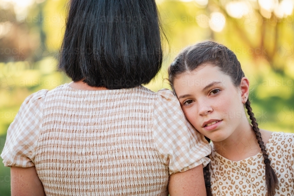 Pre-teen girl leaning on mothers shoulder in natural bush setting - Australian Stock Image