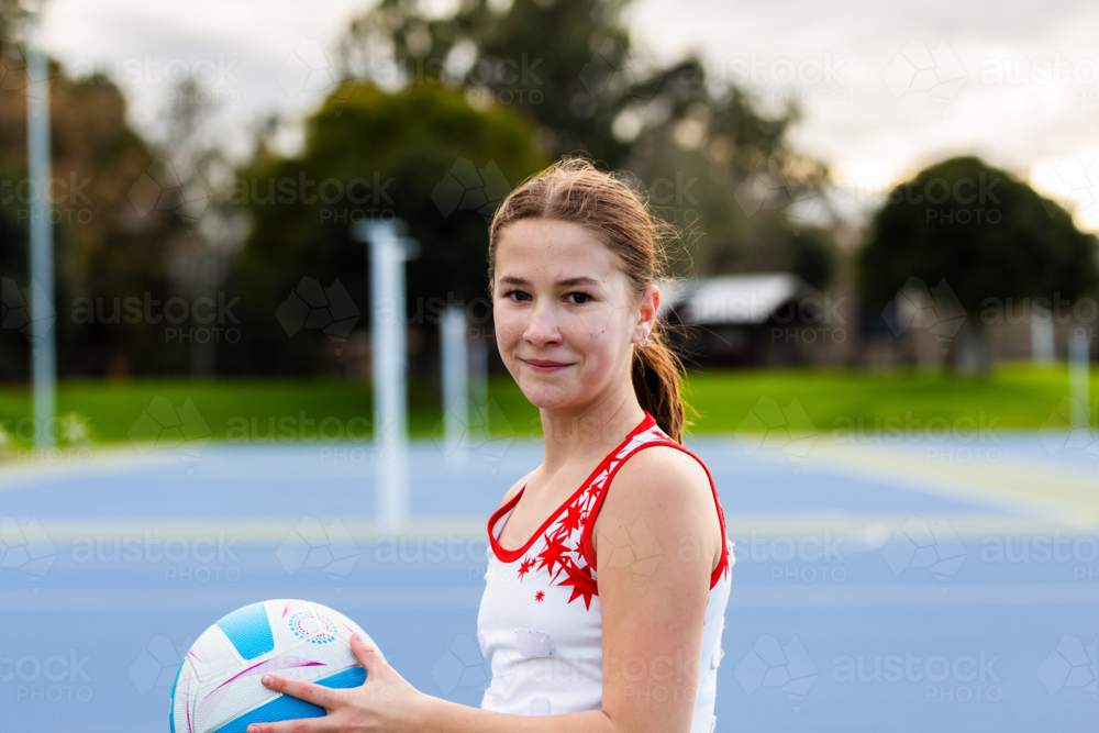 pre-teen netball player with ball on court training for sport - Australian Stock Image