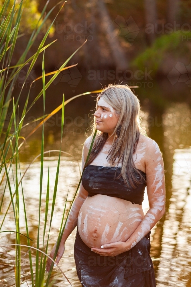 Pregnant woman in her early thirties with traditional ochre body paint - Australian Stock Image