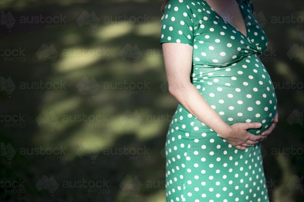 Pregnant woman standing in park. - Australian Stock Image
