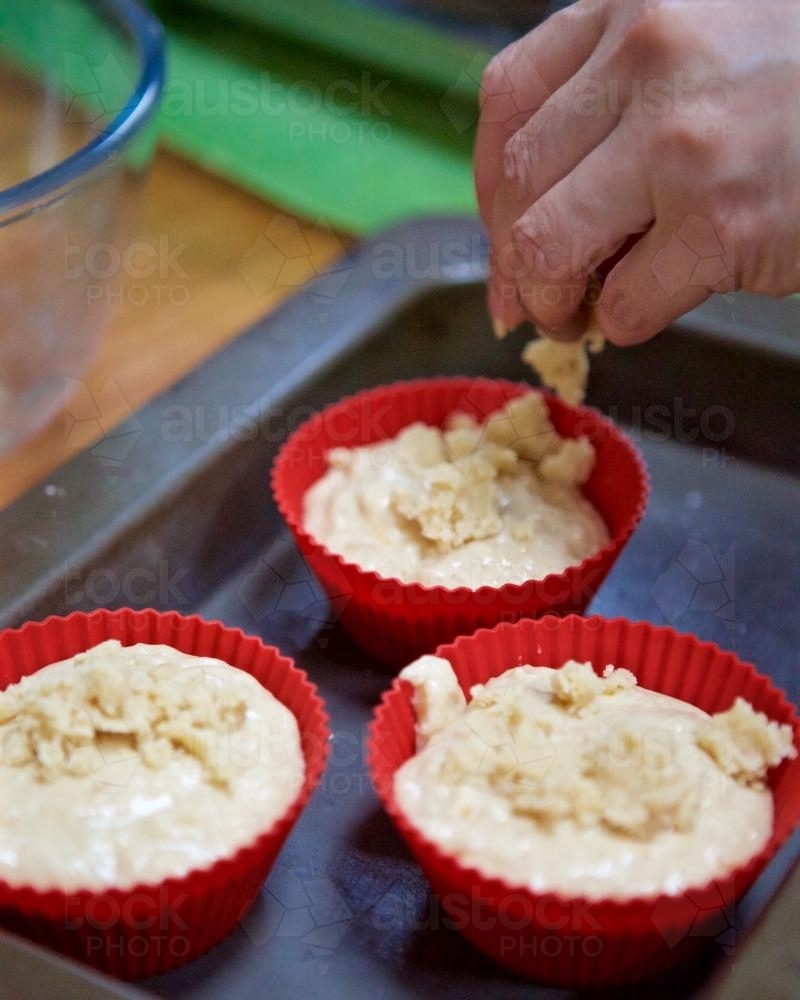 Preparing muffins in baking tray - Australian Stock Image