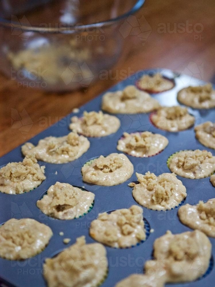 Preparing muffins in baking trays - Australian Stock Image
