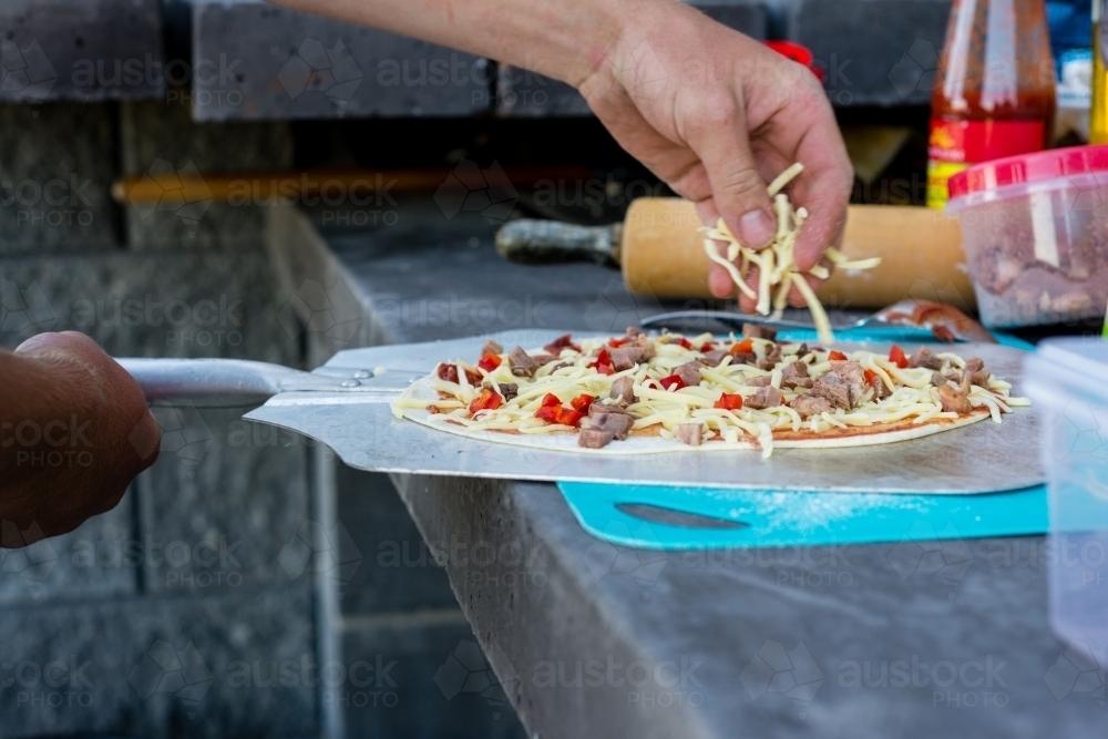 preparing pizza at an outdoor pizza oven - Australian Stock Image