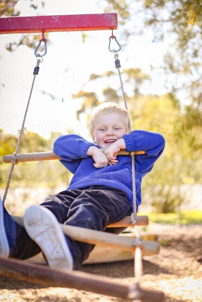 Preschool age child posing on rope ladder swing for kindergarten photos. Portrait of young boy. - Australian Stock Image