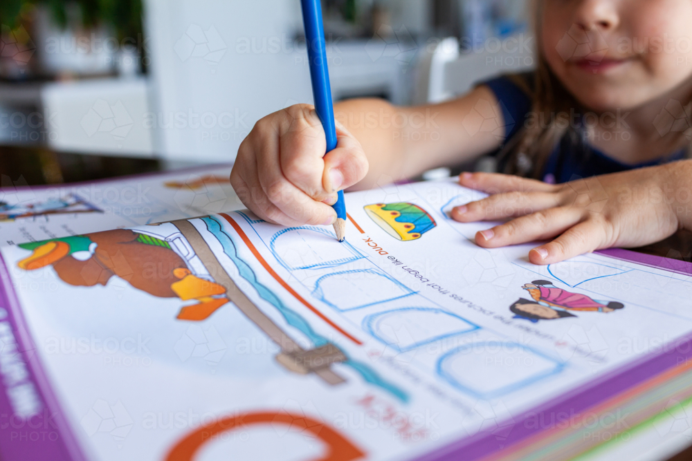 Image of Preschool aged child writing letters in workbook sitting at ...