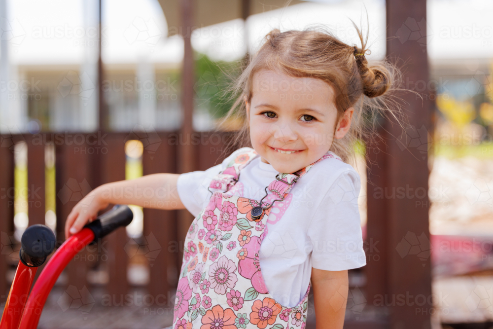 Preschool child riding bike in kindergarten yard - Australian Stock Image