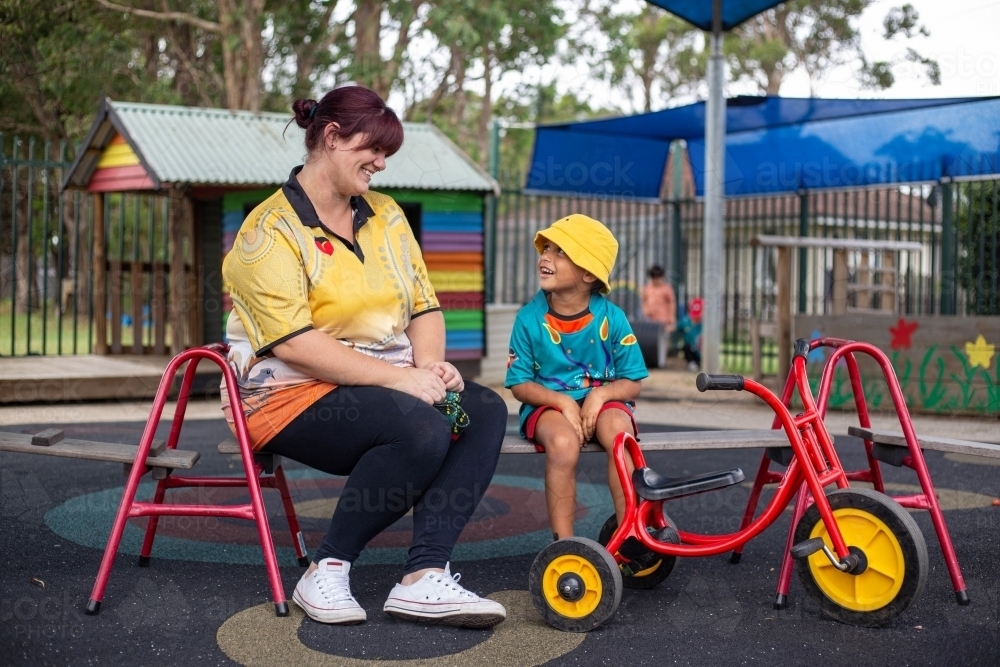 Preschool teacher and young aboriginal boy smiling at each other - Australian Stock Image