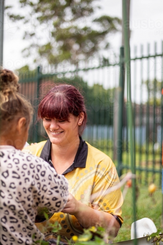 Image of Preschool teacher talking to her student and smiling
