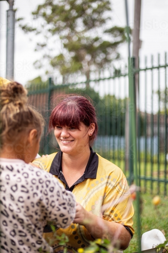 Image of Preschool teacher talking to her student and smiling