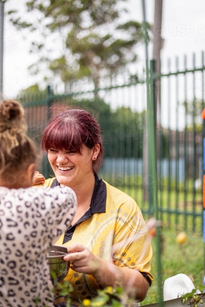 Preschool teacher talking to her student and smiling - Australian Stock Image