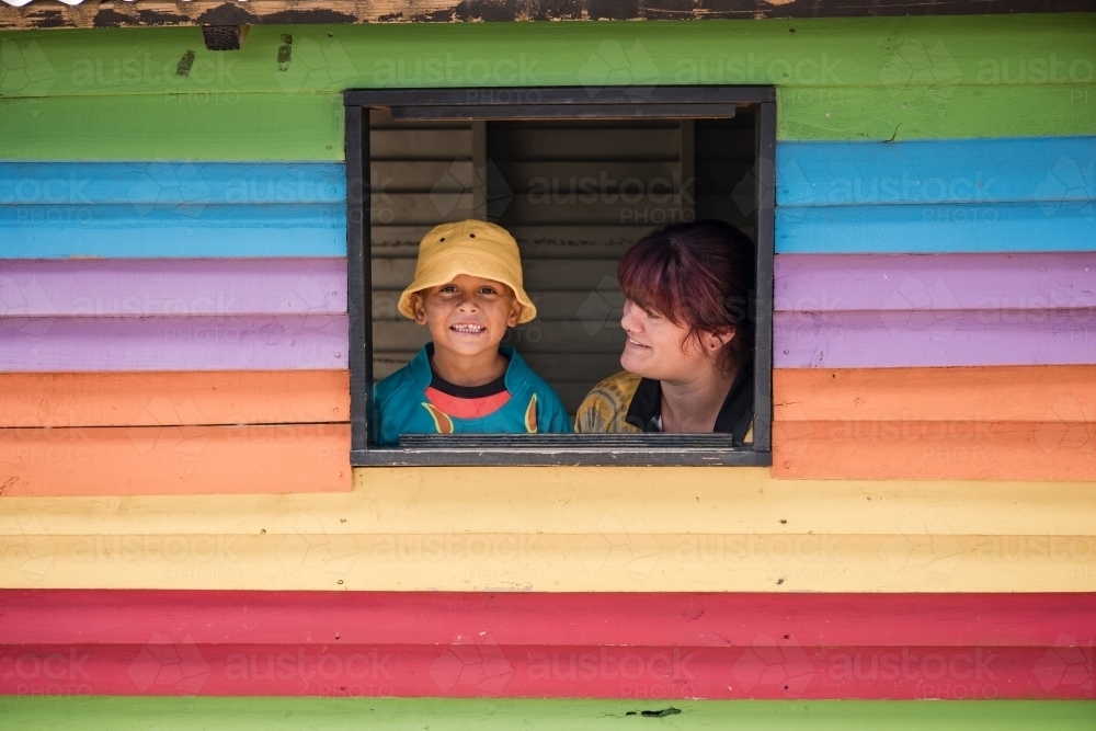 Preschool teacher with young Aboriginal  boy in cubby house window - Australian Stock Image