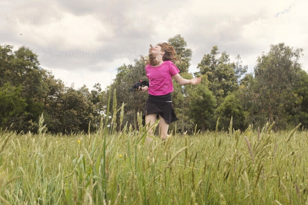 Preteen girl running happily through green paddock - Australian Stock Image