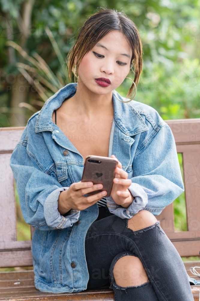 pretty asian woman looking at phone - Australian Stock Image