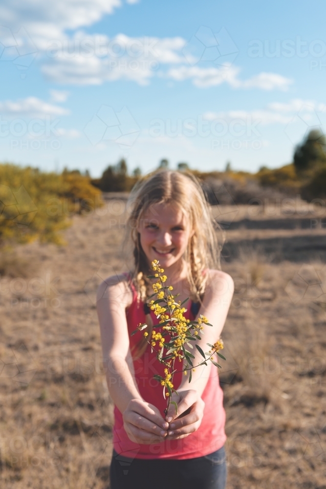 Pretty tween girl holding a branch of wattle - Australian Stock Image