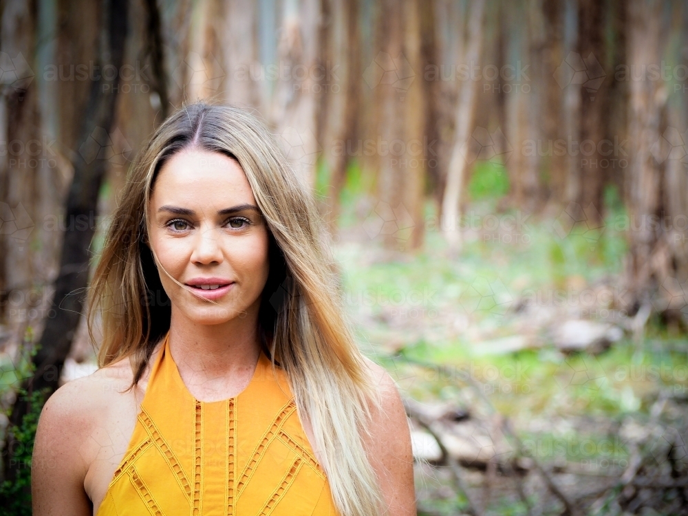 Pretty woman in trees with yellow dress - Australian Stock Image