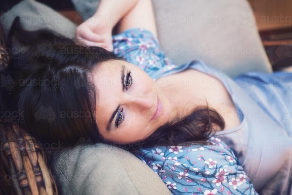 Pretty woman with beautiful eyes lying relaxing on a lounge - Australian Stock Image