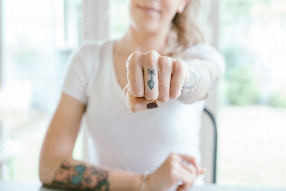 Pretty young girl punching fist towards the camera in a message of power - Australian Stock Image