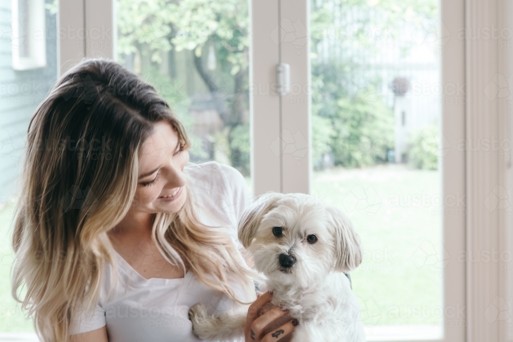 Pretty young girl with a cute little white dog on her lap - Australian Stock Image