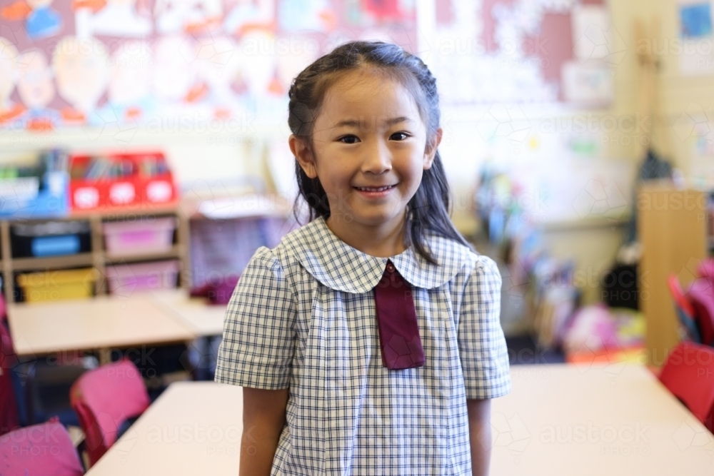 Primary age girl in classroom, smiling at camera - Australian Stock Image
