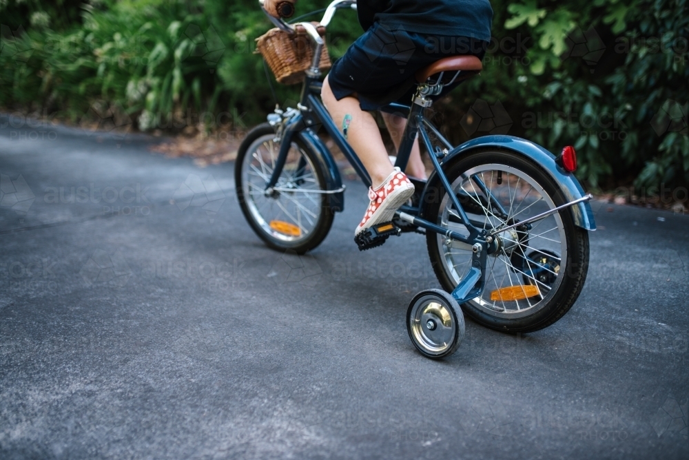 Primary aged girl rides bike on a driveway - Australian Stock Image