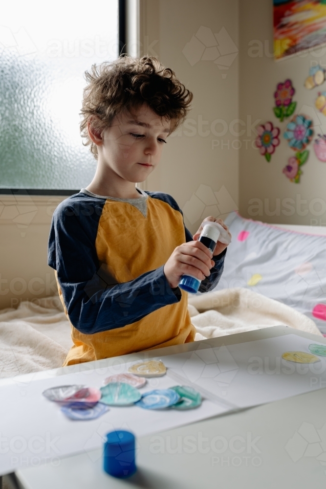 Primary school boy at home remote learning, working on maths lesson pasting numbers in order - Australian Stock Image