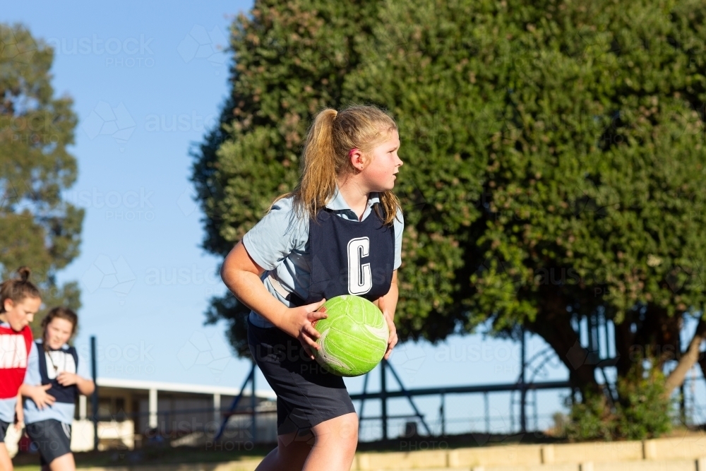 Primary school child with hearing aid playing netball - Australian Stock Image