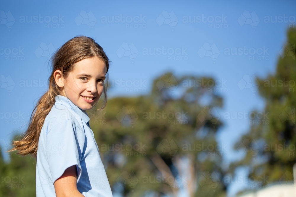 Primary school kid with ponytail looking at camera - Australian Stock Image