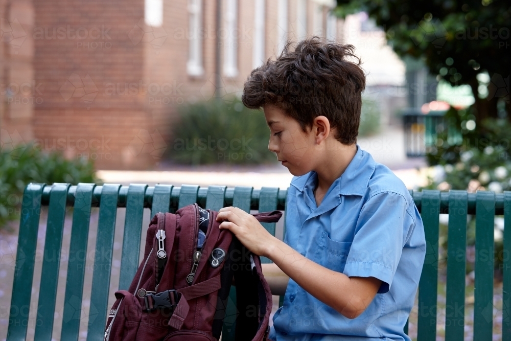 Primary school student at school looking in school bag - Australian Stock Image