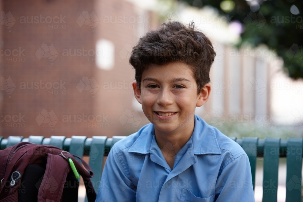 Primary school student at sitting with backpack smiling - Australian Stock Image