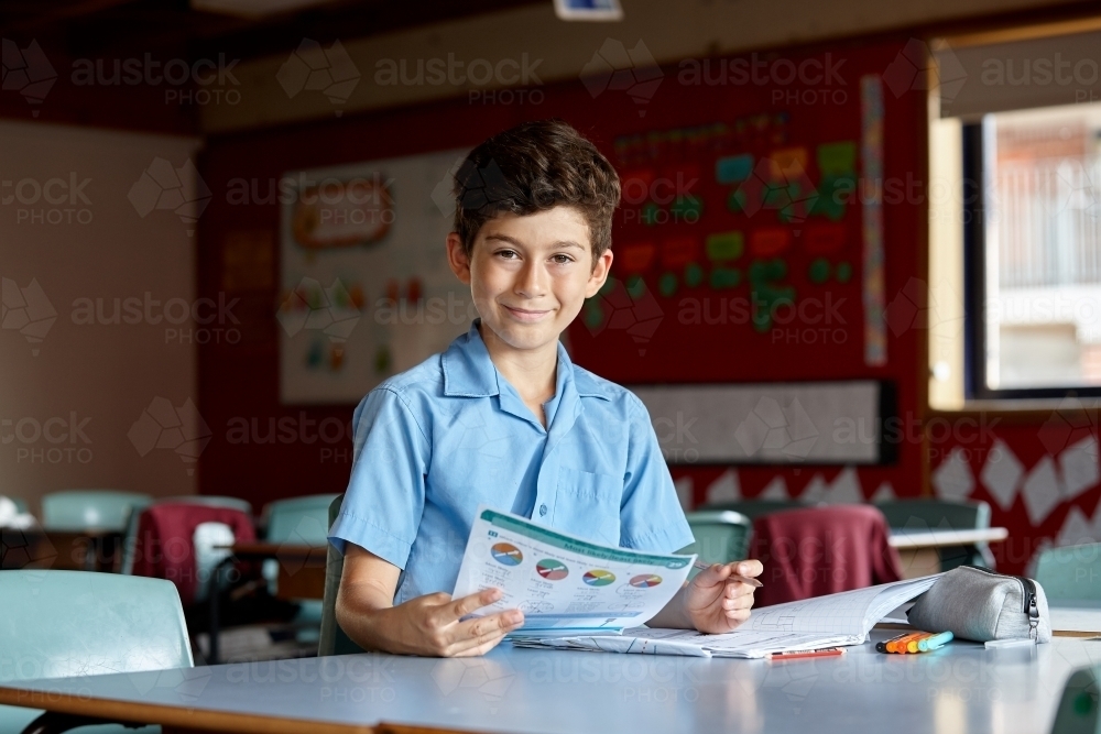 Primary school student in classroom working on homework - Australian Stock Image