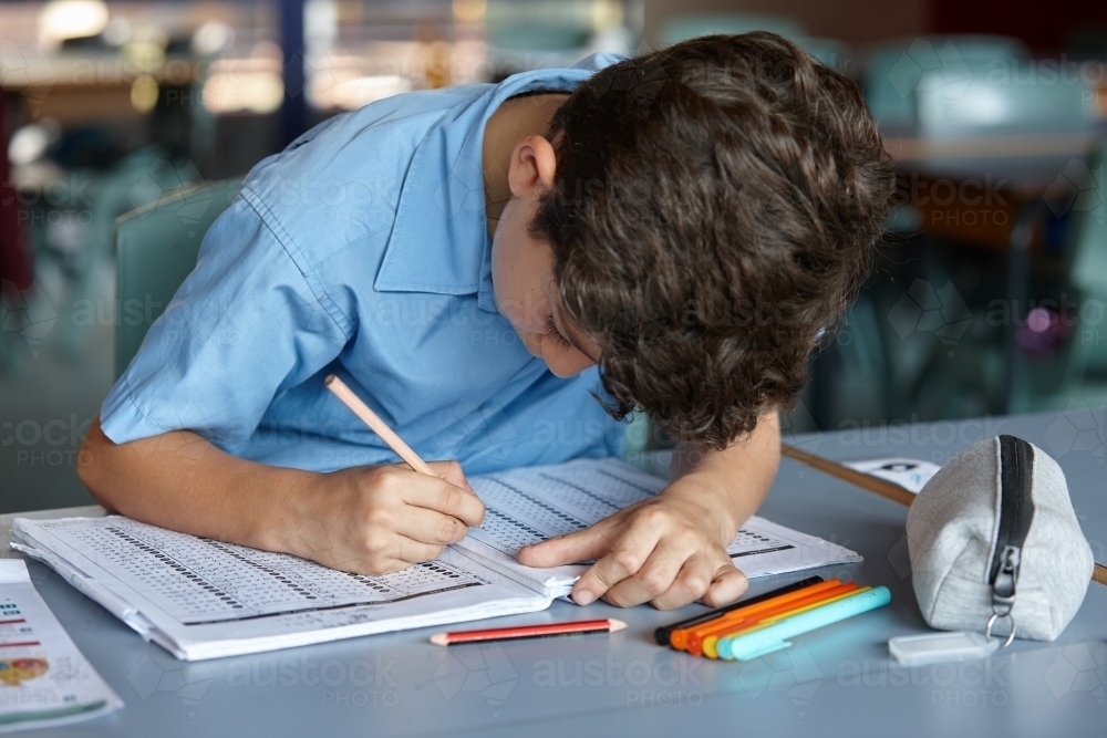 Primary school student in classroom working on homework - Australian Stock Image