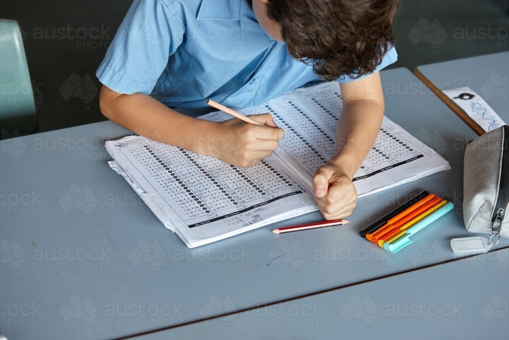 Primary school student in classroom working on homework - Australian Stock Image
