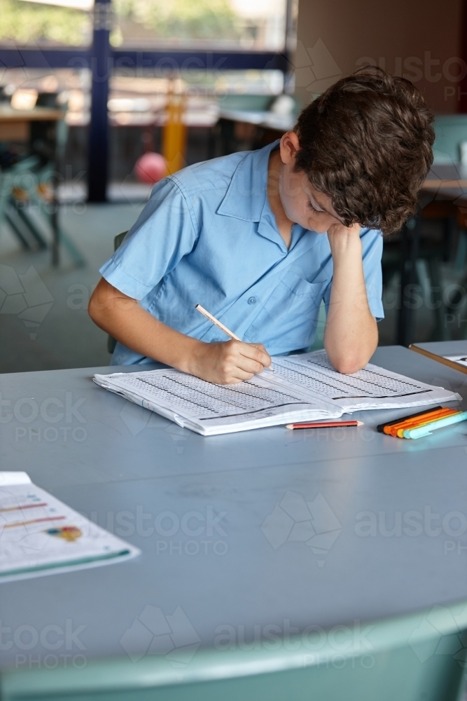 Primary school student in classroom working on homework - Australian Stock Image