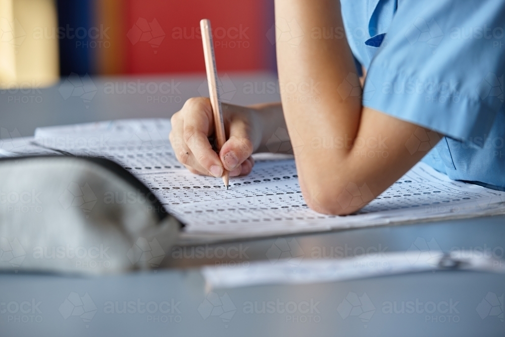 Primary school student in classroom working on homework - Australian Stock Image