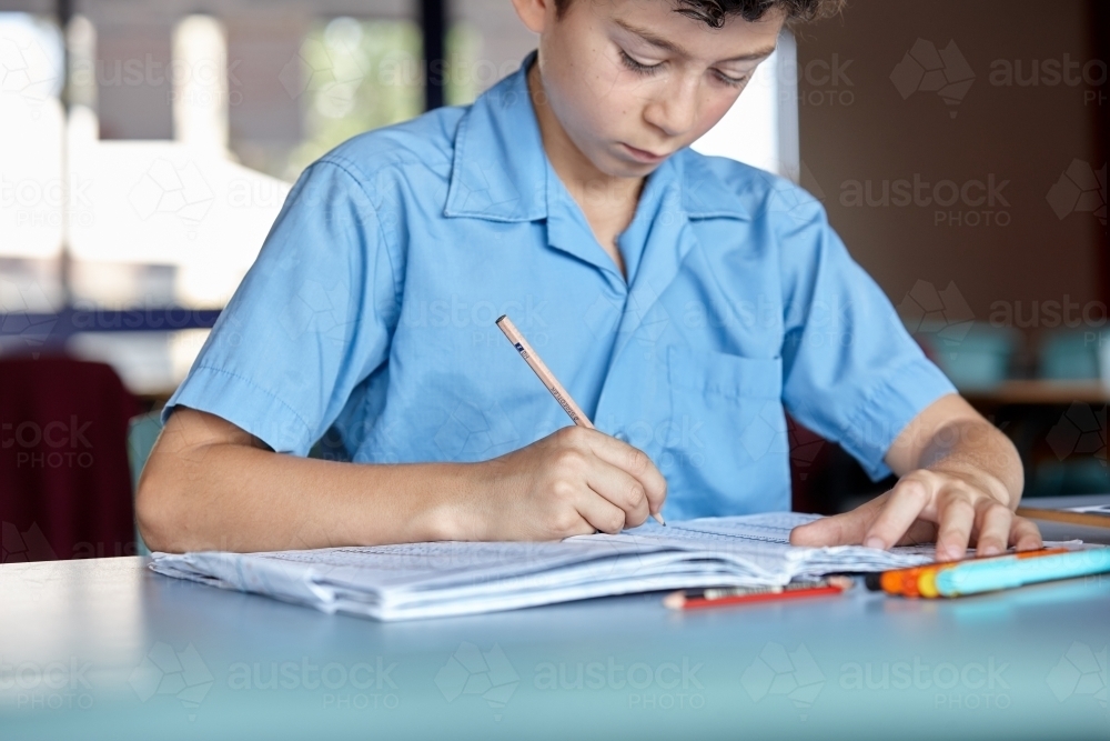 Primary school student in classroom working on homework - Australian Stock Image