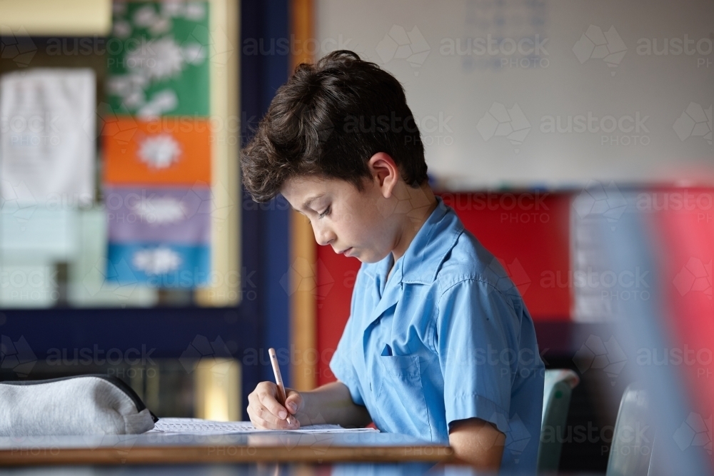 Primary school student in classroom working on homework - Australian Stock Image